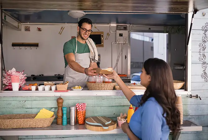 Man serving woman food out of food truck
